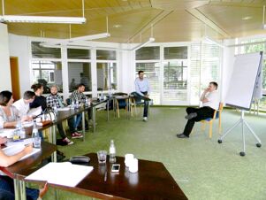 Seminarraum mit Gruppenbesprechung in modernem Sitzungsraum des Hotel Landgut Burg mit gro&szlig;en Fenstern und Flipchart