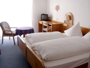 Helles Hotelzimmer mit zwei Einzelbetten, Schreibtisch, Fernseher und sitzgelegenheiten im Gasthof Schwarzer Adler.