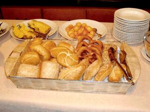 Verschiedene frische Backwaren in einem Korb und Teller mit Obst am Buffet im Gasthof Schwarzer Adler f&uuml;r ein reichhaltiges Fr&uuml;hst&uuml;ck.