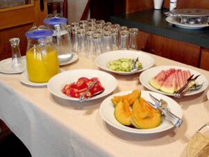 Buffet mit frischen Melonen, Tomaten, Gurkensalat und Orangensaft auf einem Tisch im Gasthof Schwarzer Adler.