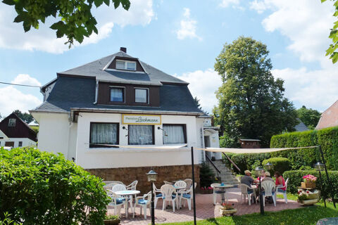 Pension Lachmann white building with outdoor seating area featuring plastic chairs and tables under a white canopy on a sunny day