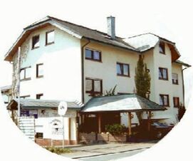 Au&szlig;enansicht des mehrst&ouml;ckigen Geb&auml;udes vom Hotel Pension Herrenberg mit wei&szlig;en W&auml;nden und braunen Fensterrahmen bei Tageslicht.