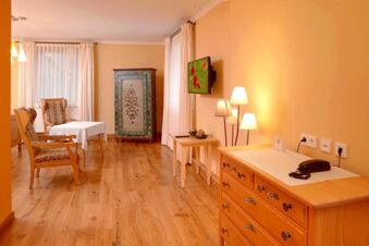 Helles Zimmer mit Holzboden, antikem Schrank, Sesseln und Fernseher in Landgasthof Haueis, gem&uuml;tlich eingerichtet.