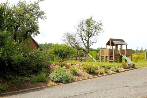 Spielplatz im Garten mit Rutsche und Schaukel vor einer gr&uuml;nen Landschaft beim Landgasthof Haueis mit B&auml;umen und Blumenbeeten