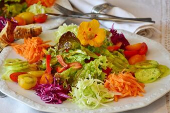 Frischer bunter Salatteller mit verschiedenen Gem&uuml;searten und essbarer Blume im Landhotel-Restaurant Mei&szlig;nerhof serviert.