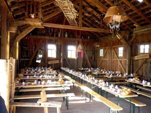 Rustikal eingerichteter Speisesaal mit langen Holztischen und B&auml;nken im Landhotel-Restaurant Mei&szlig;nerhof, gedeckt f&uuml;r G&auml;ste.