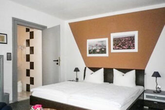 Modern eingerichtetes G&auml;stezimmer mit gro&szlig;em Bett, Nachtlampen und Bildern an der Wand im Landhotel-Restaurant Mei&szlig;nerhof.