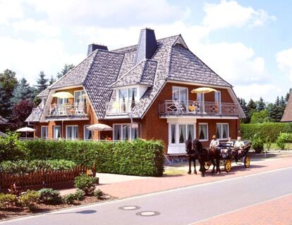 Landhaus Heide Romantisches Heidehotel Garni Nichtraucher with a brick facade, balconies, and a horse-drawn carriage on the street