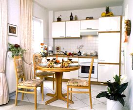 Bright kitchen dining area at Landhaus Heide Romantisches Heidehotel Garni Nichtraucher with round table, four chairs, and white cabinets