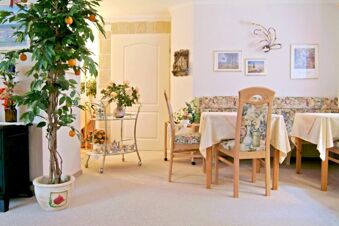 Dining area with floral chairs and tables covered in cream tablecloths at Landhaus Heide Romantisches Heidehotel Garni Nichtraucher