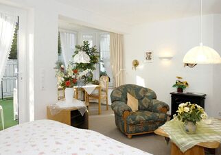 Bright hotel room at Landhaus Heide Romantisches Heidehotel Garni Nichtraucher with armchair, floral decorations, and dining table near window
