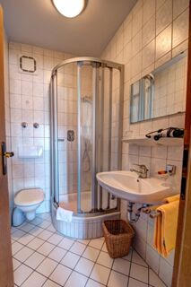 Baie compactă cu duș, toaletă și chiuvetă &icirc;n Hotelul Gasthof Huber, cu gresie și faianță și accesorii practice.