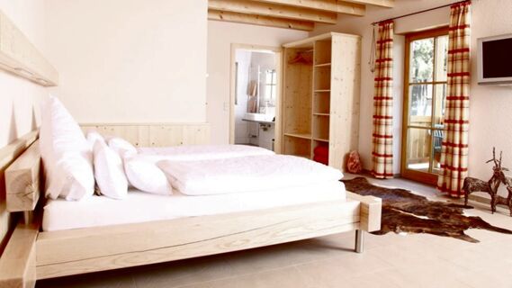 Modern eingerichtetes Hotelzimmer mit Holzm&ouml;beln und Balkon im Hotel Lochm&uuml;hle GmbH, hell und einladend gestaltet mit Bad und Fernseher.