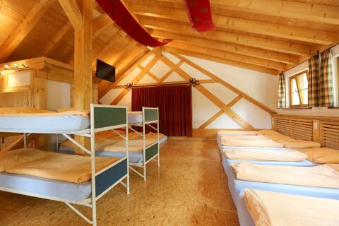 Schlafraum mit Holzbalkendecke, mehreren Betten und Stockbetten im Hotel Lochm&uuml;hle GmbH in rustikalem Stil mit Tageslichtfenstern.