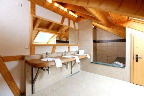 Helles Badezimmer mit Holzbalken und doppeltem Waschbecken sowie Dusche, gestaltet im skandinavischen Stil im Hotel Lochm&uuml;hle GmbH.