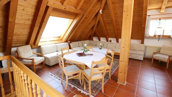 Gem&uuml;tlicher Gemeinschaftsraum mit Holzw&auml;nden, Sitzbereich und einem Tisch im Hotel Lochm&uuml;hle GmbH, ideal zum Entspannen und Treffen.