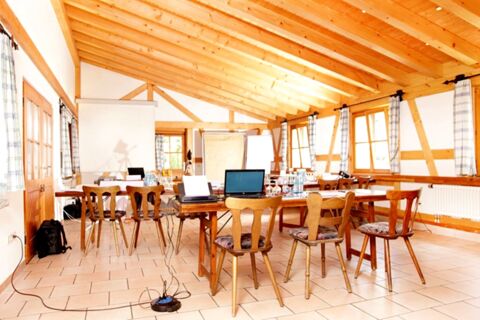 Hell erleuchteter Seminarraum mit Holzbalkendecke und Tischen f&uuml;r Meetings im Hotel Lochm&uuml;hle GmbH in traditionellem Stil.