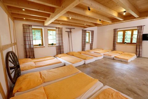 Mehrbettzimmer mit zehn Betten und orangenen Decken in einem rustikalen Raum mit Holzdecke im Hotel Lochm&uuml;hle GmbH.