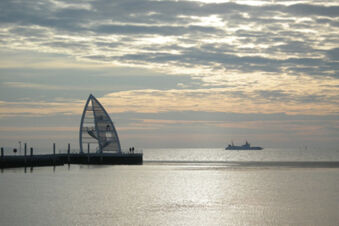 Blick auf das Wattenmeer bei Sonnenuntergang mit einer Aussichtsplattform am Pier im Vordergrund, im Kontext von Meyenburg & Gerds H&ouml;ft Appartements am Wattenmeer.