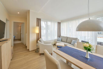 Helles und modern eingerichtetes Wohnzimmer mit Esstisch und Sofa in den Meyenburg & Gerds H&ouml;ft Appartements am Wattenmeer.