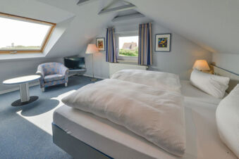 Gem&uuml;tliches Hotelzimmer mit Doppelbett, Sessel und Fenster mit Blick, typisch f&uuml;r Meyenburg & Gerds H&ouml;ft Appartements am Wattenmeer.