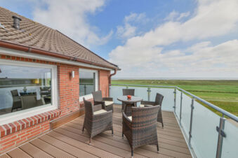 Balkon mit vier St&uuml;hlen und Tisch mit Blick auf gr&uuml;ne Wiesen bei Meyenburg & Gerds H&ouml;ft Appartements am Wattenmeer.