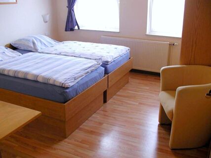 Lihtsalt sisustatud kahe voodi, heleda puitp&otilde;randa ja siniste kardinatega akendega tuba Marina's holiday flats'is.