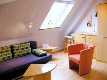 Living room in Marinas Ferienwohnungen with a blue sofa, checkered cushions, a coral armchair, wooden tables, and a skylight window