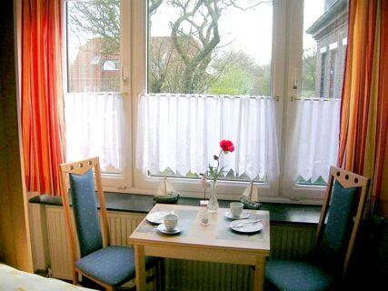 Hubane s&ouml;&ouml;gituba koos v&auml;ikese puidust laua, kahe tooli ja lillevaasiga suure akna ees Marina korteris.