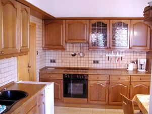 Traditional wooden kitchen cabinets with tiled backsplash, an oven, coffee maker, and a sink in Marinas Ferienwohnungen