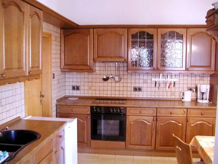 Traditional wooden kitchen cabinets with tiled backsplash, an oven, coffee maker, and a sink in Marinas Ferienwohnungen