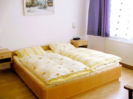 Twin bed with floral and striped bedding in a bright room at Marinas Ferienwohnungen with nightstands and curtains