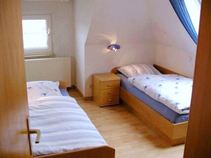 Two single beds with striped and floral bedding facing each other in a wooden floored room at Marinas Ferienwohnungen