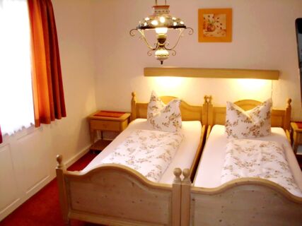 Gem&uuml;tliches Doppelzimmer mit zwei Einzelbetten, floralem Bettbezug und Holzm&ouml;beln im Hotel-Restaurant zum Wilden Mann.