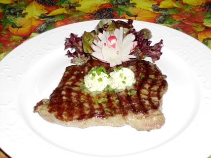 Gegrilltes Steak serviert mit einem Klecks Kr&auml;uterbutter und einem kleinen Salat auf einem wei&szlig;en Teller im Hotel-Restaurant zum Wilden Mann.