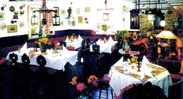 Gem&uuml;tlich dekorierter Gastraum mit wei&szlig;en Tischdecken, bunten Blumen und jagdlichen Dekorationen im Hotel-Restaurant zum Wilden Mann.