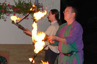 Two men performing fire juggling with torches outside a building at night near Gasthof Lamm Hotel und Restaurant