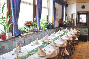 在 Gasthof Lamm Hotel and Restaurant 餐廳中，擺放了布藝餐巾、蠟燭和植物的長餐桌，洋溢著節日的溫馨氣氛。