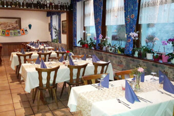 Gasthof Lamm Hotel and Restaurant 舒適的餐廳區域，擺放著餐桌、藍色餐巾和花卉裝飾。