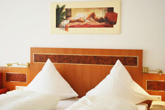 A room at Gasthof Lamm Hotel und Restaurant featuring two white pillows and beds with a wooden headboard and wall painting above the bed