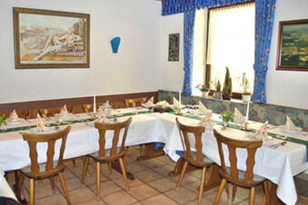 Dining area with wooden chairs, white linens, folded napkins, candlesticks, artwork, and blue curtains at Gasthof Lamm Hotel und Restaurant