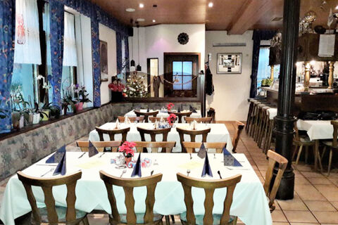 Dining area with wooden chairs and tables set with white tablecloths, napkins, and flowers at Gasthof Lamm Hotel und Restaurant