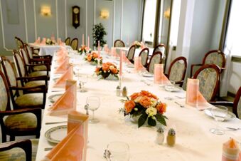 Feestelijk gedekte lange tafel met roze servetten, kaarsen en bloemstukken in het restaurant van Gasthof Basedau.