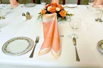 Een elegant gedekte tafel met bloemstukken en roze servetten bij Gasthof Basedau, uitnodigend en feestelijk versierd.