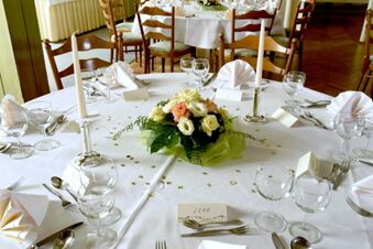 Feestelijk gedekte ronde tafel bij Gasthof Basedau met kaarsen, bloemstukken en naamkaartjes voor een stijlvol evenement.