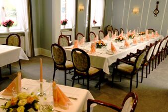 Feestelijk versierde eetzaal met lange tafels, decoratieve bloemstukken en ramen bij Gasthof Basedau.