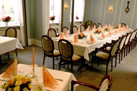 Feestelijk versierde eetzaal met lange tafels, decoratieve bloemstukken en ramen bij Gasthof Basedau.