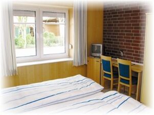 Hotel & Appartements Klostermannのダブルベッド、デスク、テレビが備わる明るい内装の客室で、田園地帯の景色を眺めることができます。