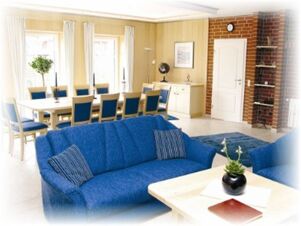 Hotel & Appartements Klostermannの明るく広々としたラウンジには、青いソファ、長いダイニングテーブル、大きな窓がある。