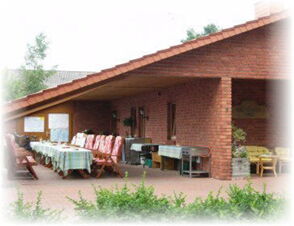 Hotel & Appartements Klostermannの建物の前に、テーブルと赤い椅子が置かれた屋外エリアがあり、共同での食事に適している。